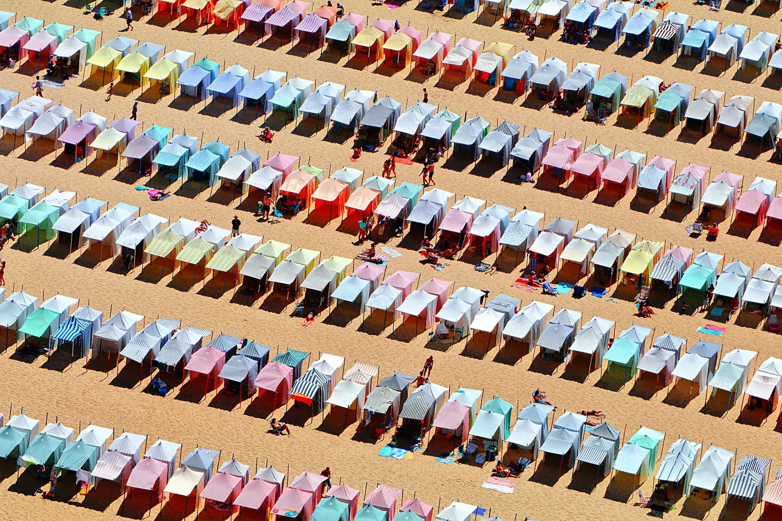 Luftaufnahme von bunten Strandzelten in Nazaré, Portugal, die Sommerstimmung einfangen.