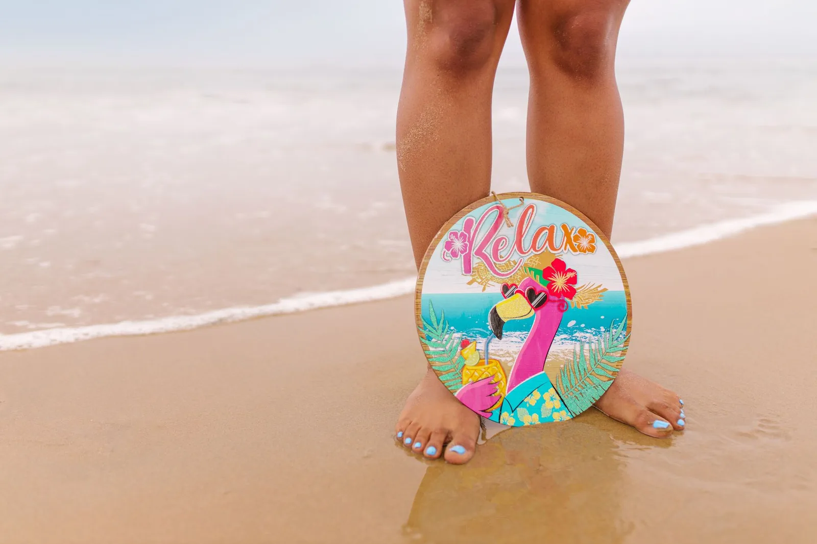 Zanderig strand met kleurrijke flamingo-kunst en een ontspannen sfeer.