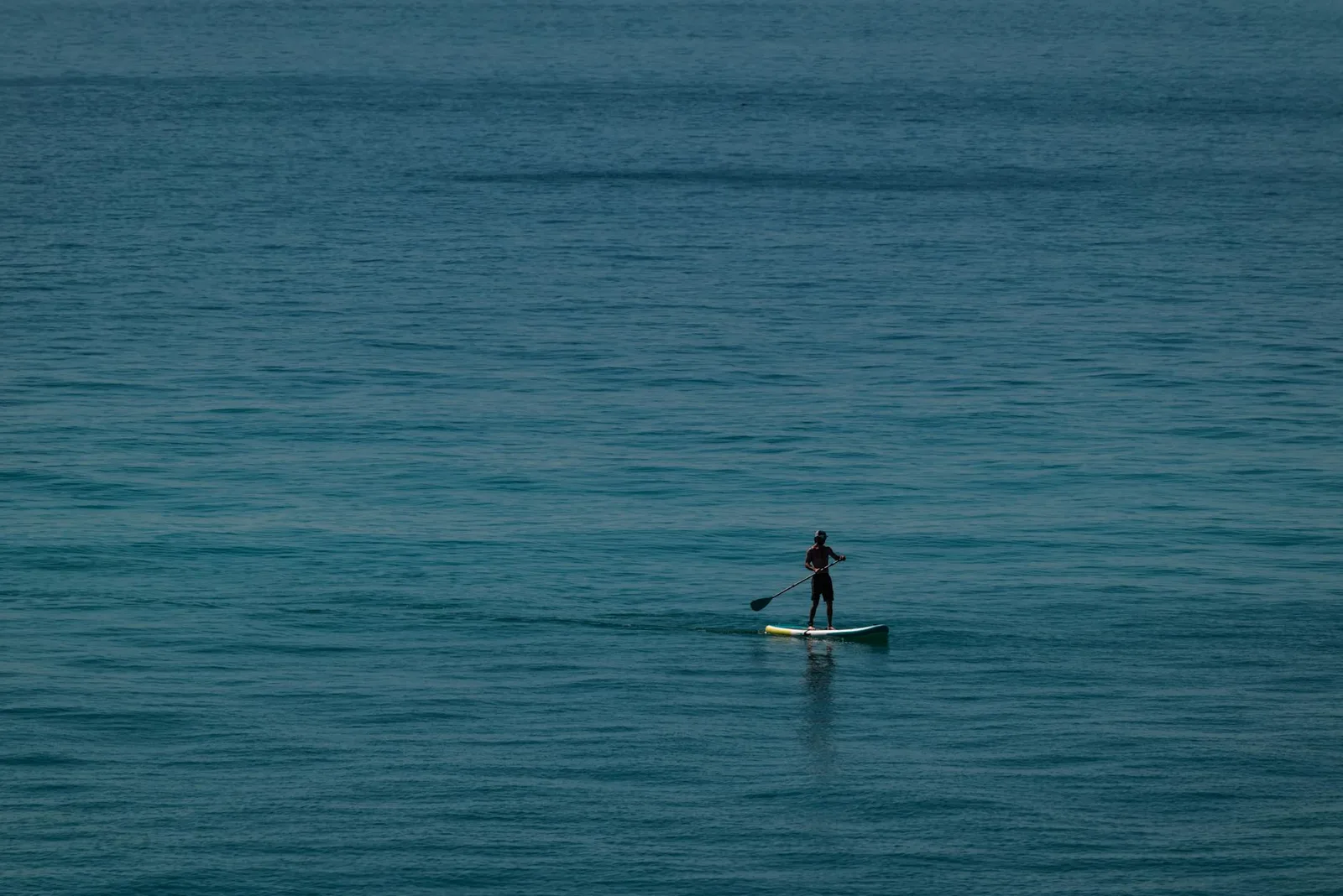 Lone paddleboarder enjoys a tranquil ride on the open ocean, embodying ultimate freedom and adventure.