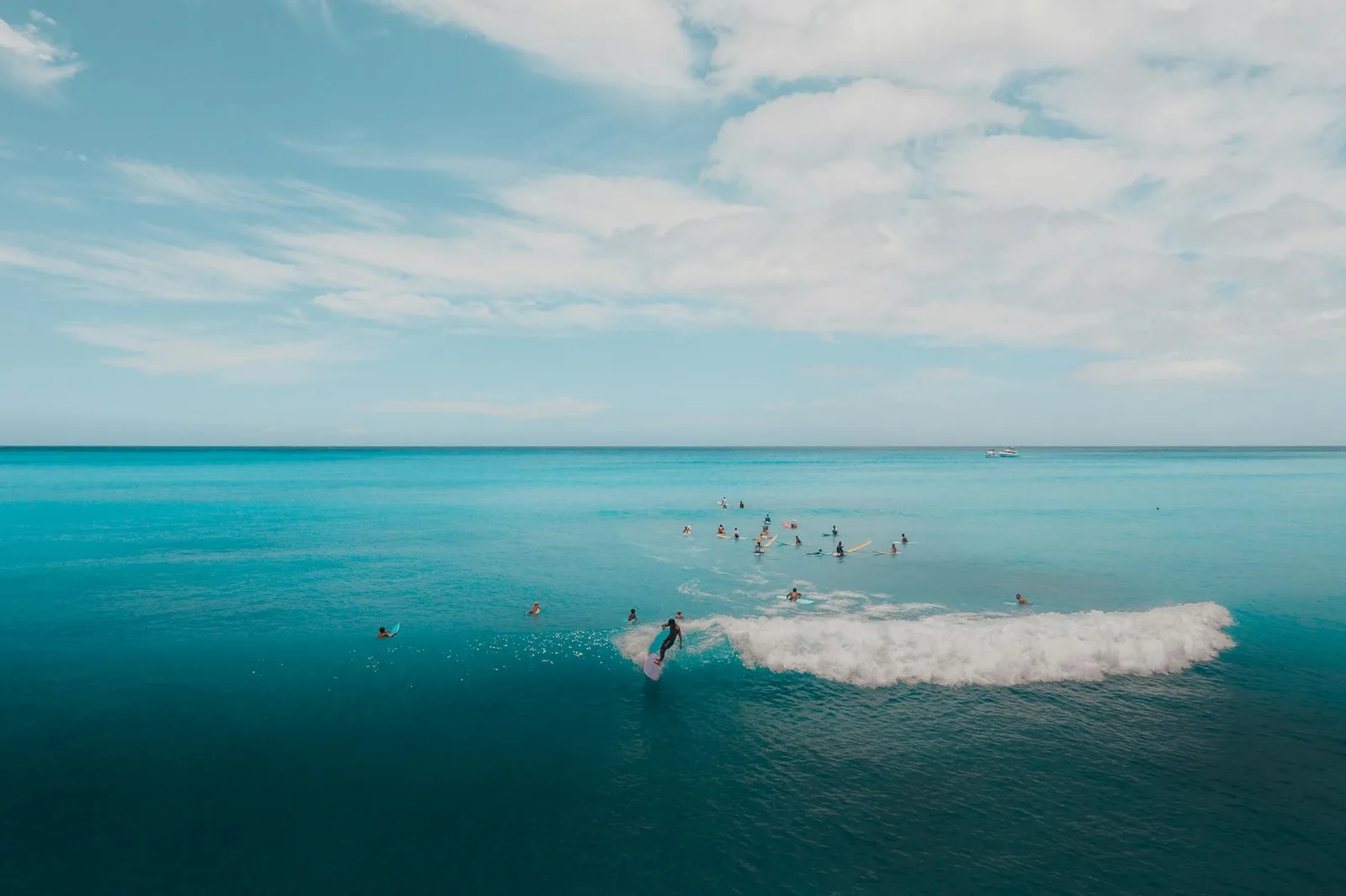 A group of surfers enjoy clear blue ocean waves under a bright sky, perfect for summer adventure.